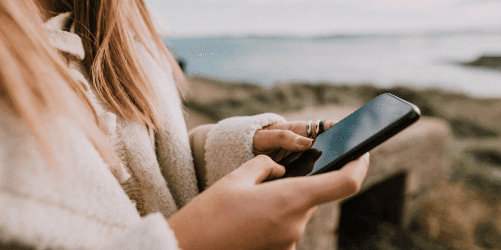 An image of a woman looking at her phone suggesting that if someone takes a while to respond to your texts they may be playing hard to get. If they don't reply at all, then they're not interested in you.