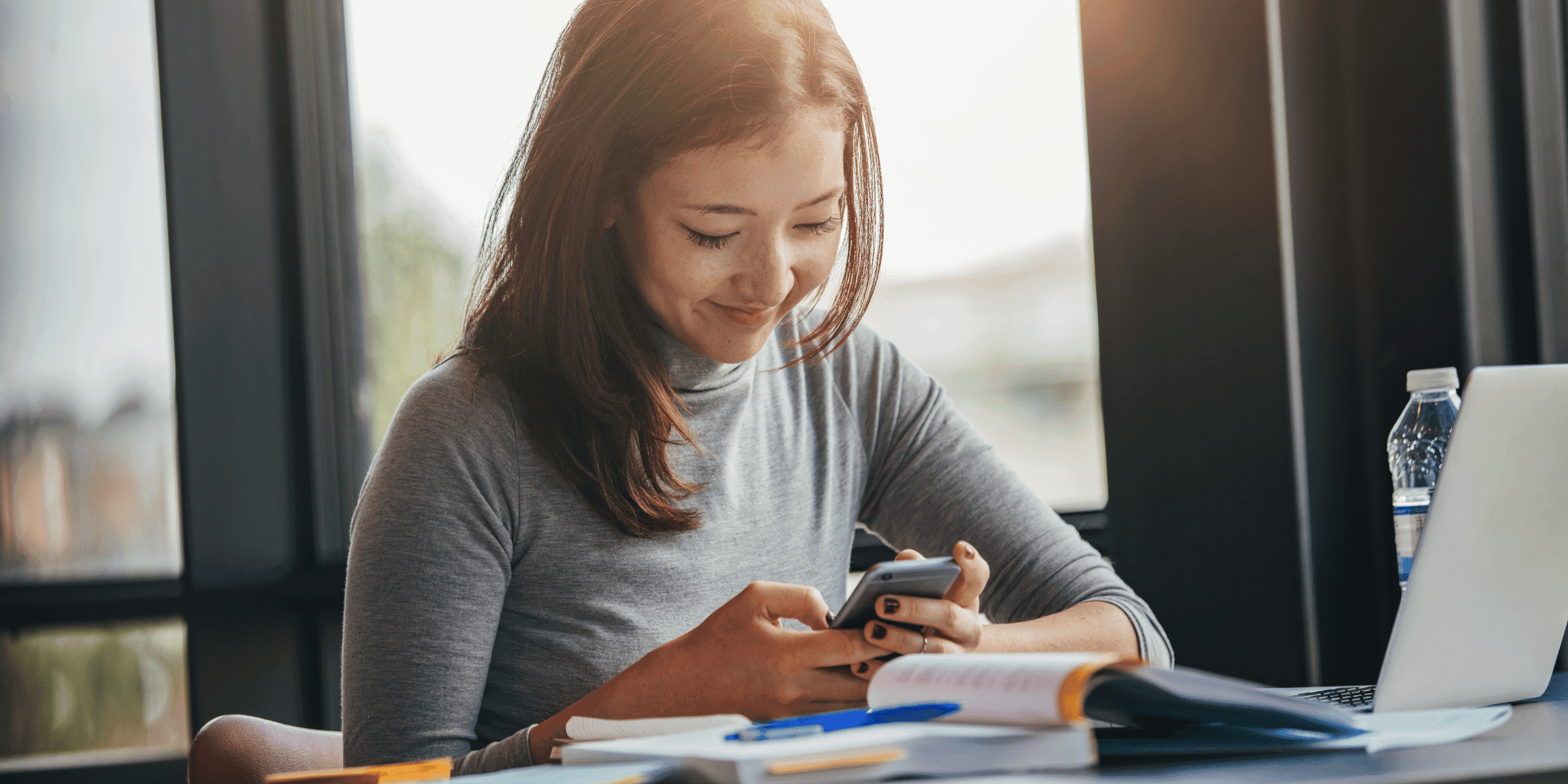 A girl smiling while reading text messages from a crush on her phone.