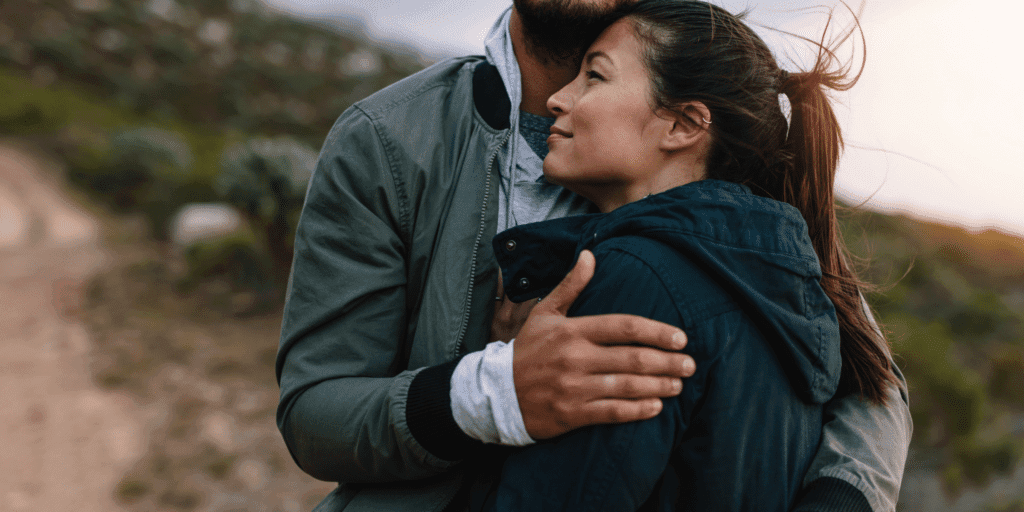 A happy couple embrace contently with each other as the wind blows through their hair.
