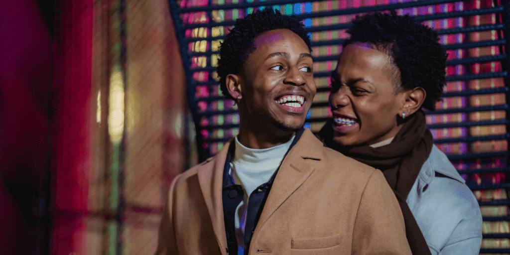 An African American male couple laugh together while on a date.