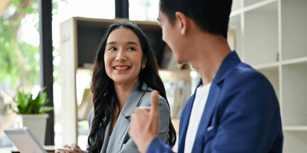 Do pay them a compliment when turning down another date. A woman in a gray suit smiles at a man in a blue sport coat in an office setting.