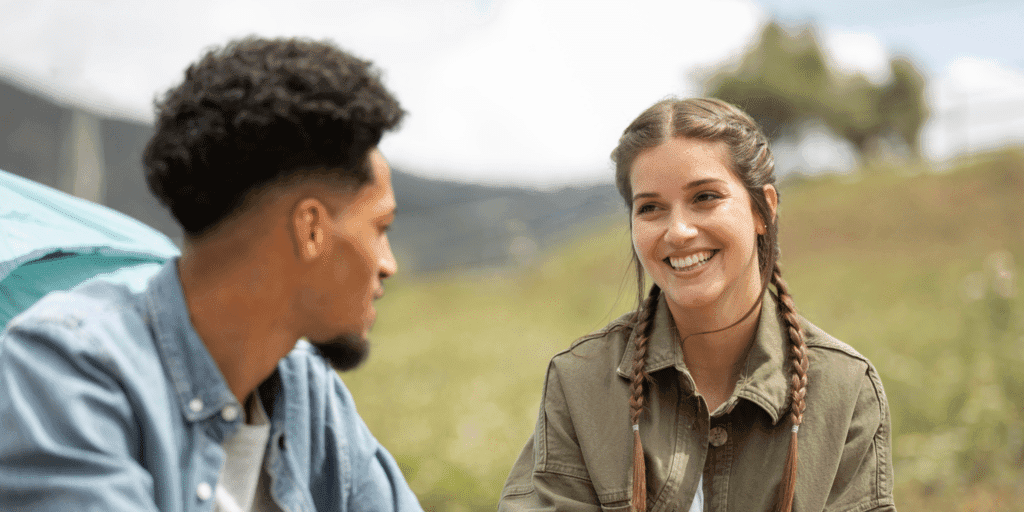 Pick up on social cues when you approach a girl. This image show a woman smiling at the man as a sign that she is interested in talking to him.