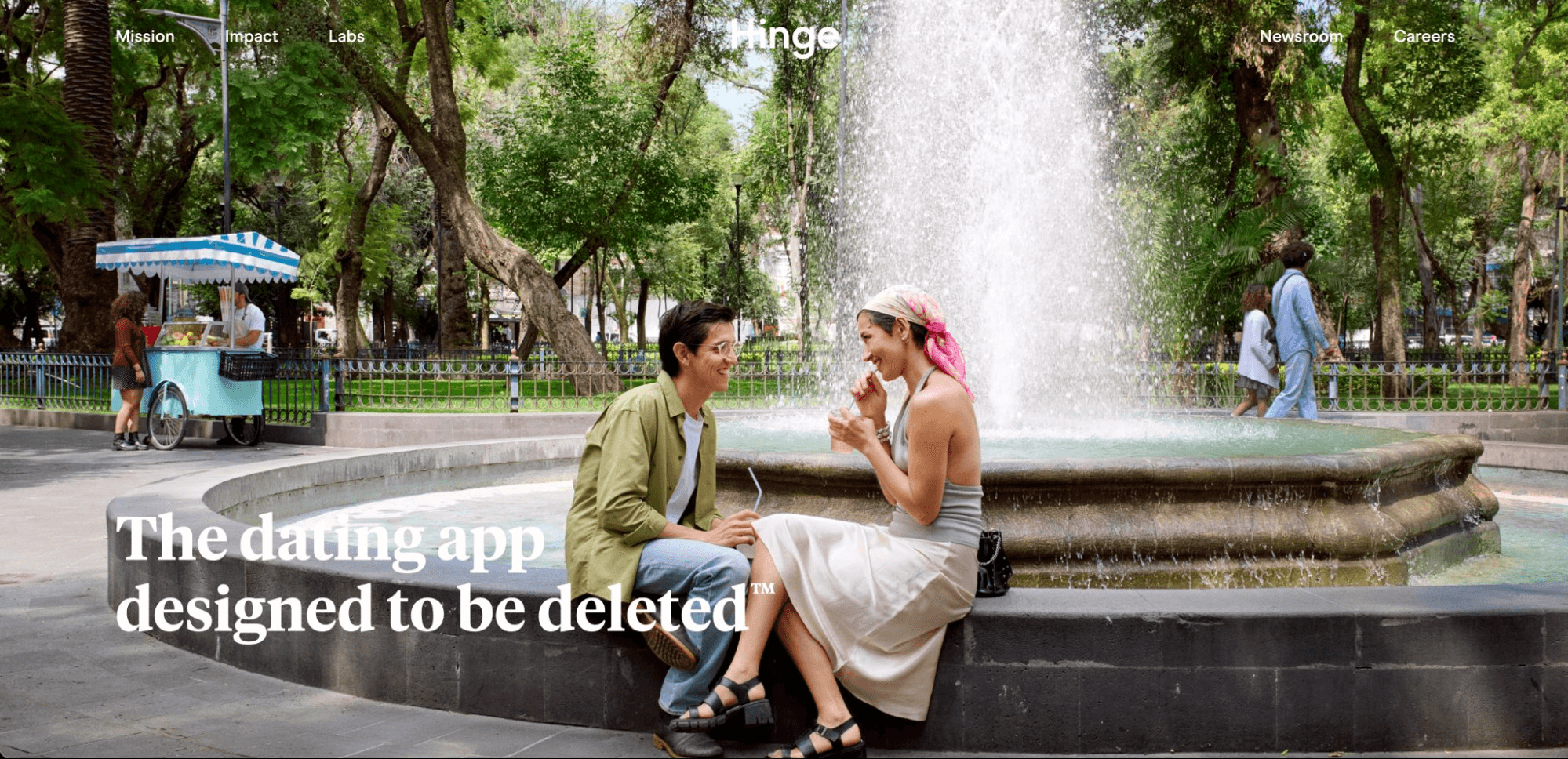 Hinge homepage showing a couple chatting by a park fountain beside the tagline "the dating app designed to be deleted"