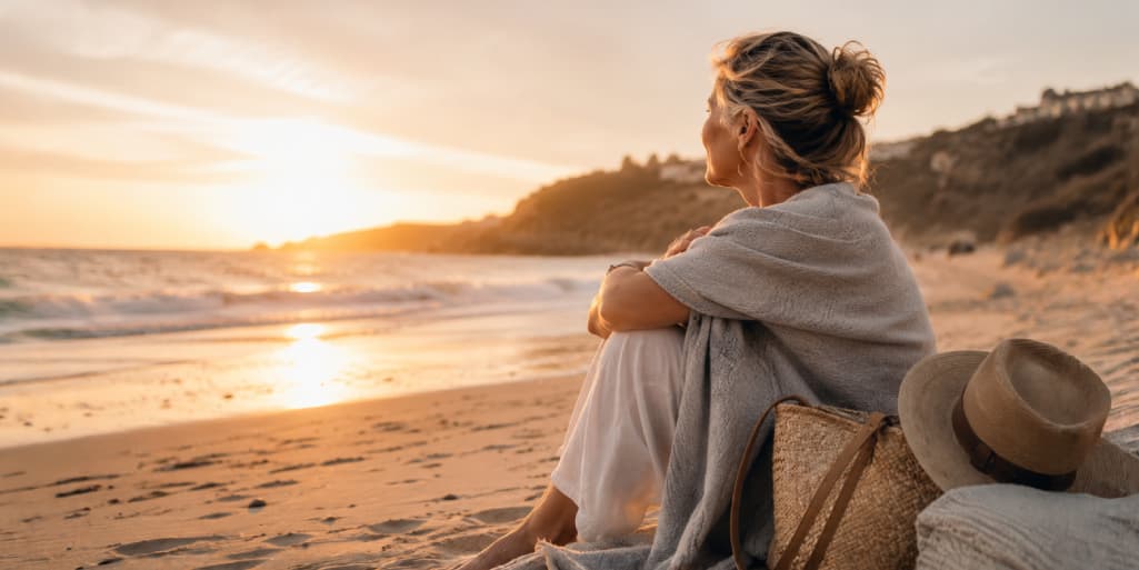 Widowed woman sitting alone on a beach at sunset, reflecting on grief, healing, and whether she is ready to begin dating again.