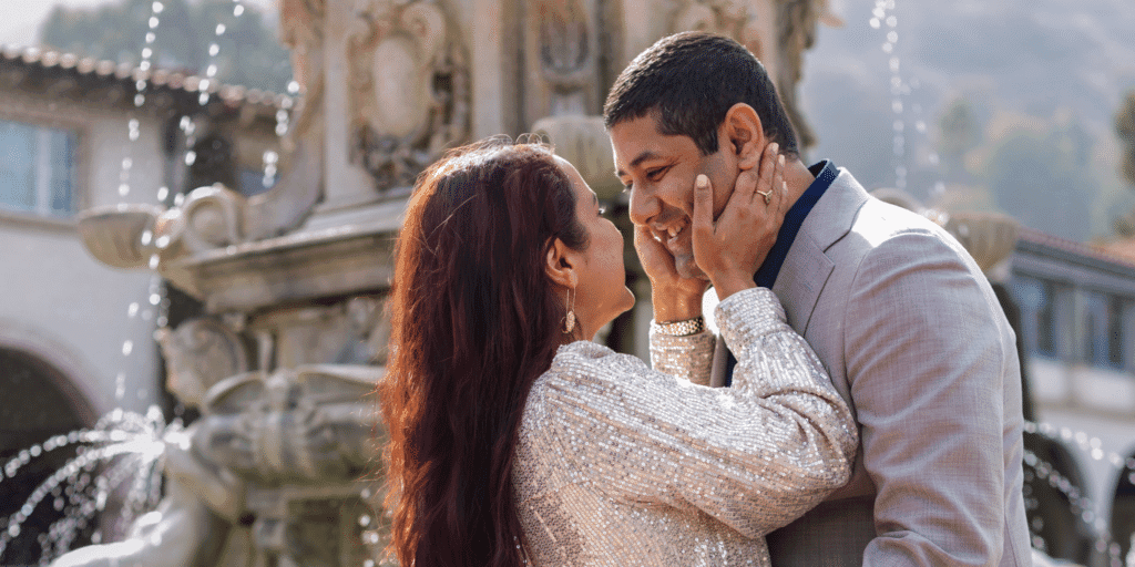 Look for initial signs of compatibility. A woman holds a man's face as they embrace each other in front of a water fountain.