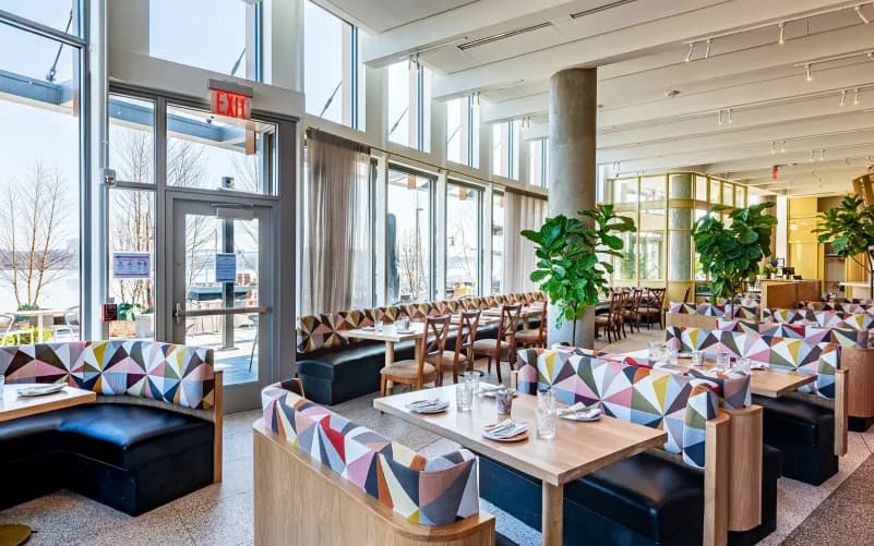 Interior of Ada’s on the River in Old Town Alexandria, featuring bright waterfront dining with floor-to-ceiling windows and views toward the Potomac.